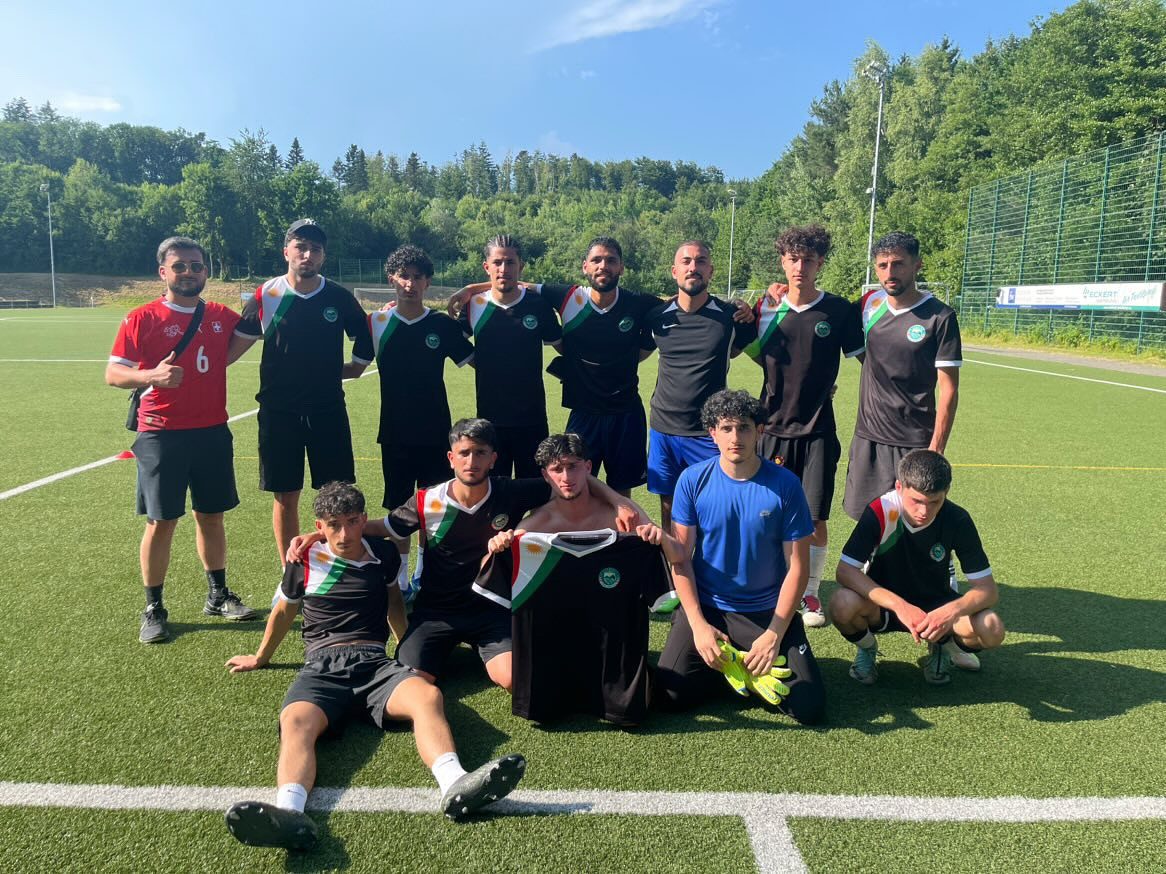 Kurdisches Diaspora-Fußballteam in schwarzen Kurdistan Trikots, zusammen auf dem Platz